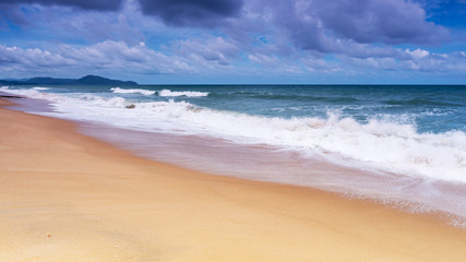 Beautiful Tropical sandy beach with blue ocean and blue sky background and wave crashing on sandy shore
