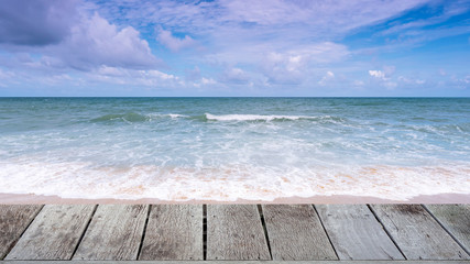 Wood floor on Beautiful Tropical sandy beach with blue ocean and blue sky background and wave crashing on sandy shore