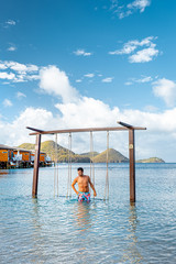 young men walking on the beach in swim short, tanning guy on the white beach by the ocean on luxury...