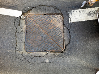 cracked asphalt around manhole cover