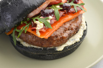delicious black Burger with cherry cheese and bacon on a green plate