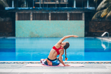 Naklejka premium Woman Yoga near swimming pool - outdoor relax in nature