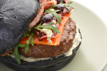delicious black Burger with cherry cheese and bacon on a green plate