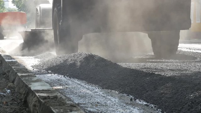 Road construction works, repair of a highway, The tractor is leveling gravel on the road, making a base for laying the asphalt
