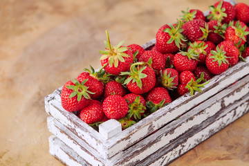 Strawberries in a box on brown concrete background
