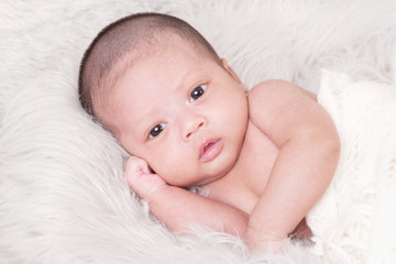 Adorable asian newborn baby in wrap sleeping on white blanket background. Portrait of newborn boy sleep on bed. open eyes.