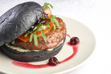 delicious black Burger with cherry cheese and bacon on a green plate