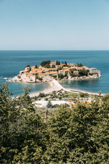 Naklejka na ściany i meble Atmospheric tourist views of the old town from the mountain. The picturesque coast of the island of Sveti Stefan.