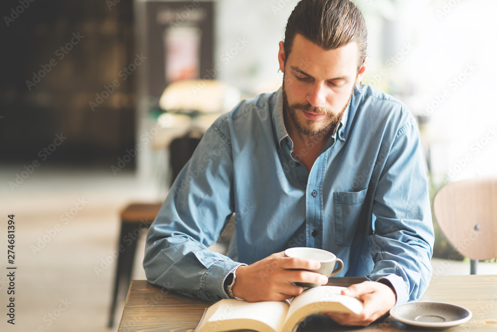 Wall mural Male freelancer in blue shirt reading a book.