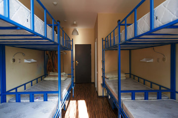 Hostel dormitory beds arranged in dorm room - obrazy, fototapety, plakaty