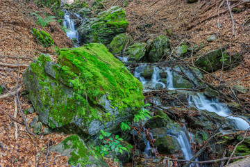 Beautiful waterfall and large  rock covered with moss