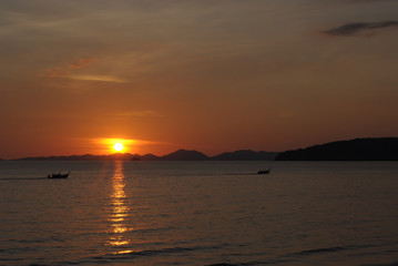 Tropical sunset, ship silhouette in ocean over evening sunlight