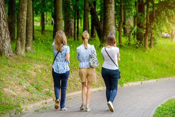 Obraz premium Three girls walk in the summer Park 