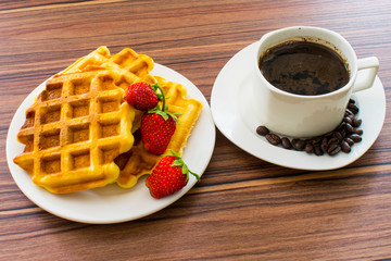 Viennese waffles with strawberries and a cup of coffee.