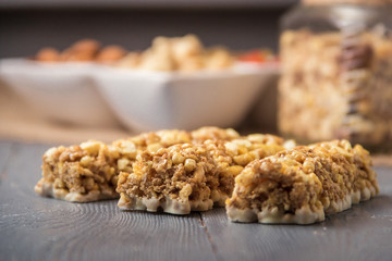 Granola bars cereal flakes with dried fruit, nuts on gray wooden table.