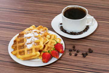 Viennese waffles sprinkled with powdered sugar, with strawberries and a cup of coffee.