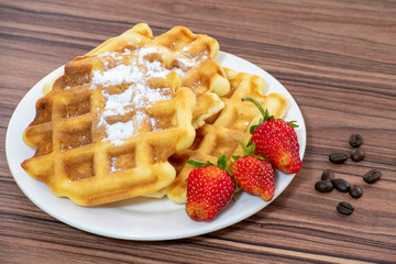 Viennese waffles sprinkled with powdered sugar with strawberries.