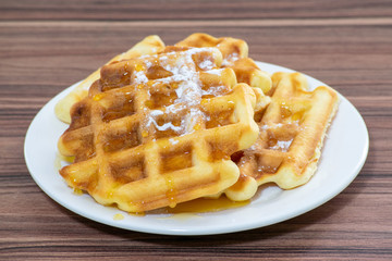 Viennese waffles sprinkled with powdered sugar and drizzled with honey.