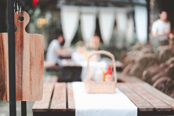 wooden cutting board ready yo use at restaurant with blurred customer and waiter, retro tone