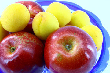 Apples and apricots in a blue vase