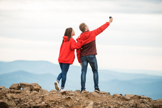 Young couple doing a selfie at the camera. on the background of beautiful mountains. The concept of travel, lifestyle. nature bright Sunny day. the rest of the loved ones. Stand back.