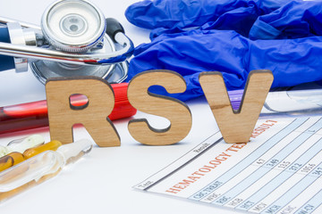 RSV laboratory medical abbreviation Respiratory Syncytial Virus test concept photo. On table is laboratory acronym RSV next to tubes of blood, other biological fluids, result analysis, stethoscope