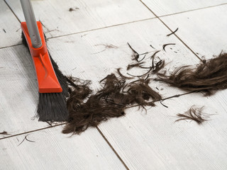 Hairdresser sweeping hair clippings on floor in barber shop
