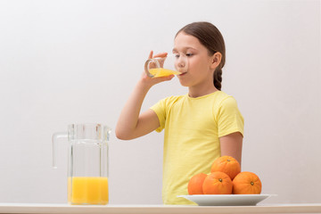 Obraz premium little girl drinks orange juice, a child enjoys a drink