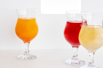 Cocktails on the white table and against the background of a white wall. cocktails of red, orange and powdery colors with glitter. summer drinks