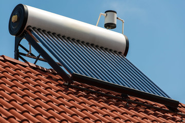 Solar water heater boiler on rooftop close up shot, blue sky background. © Alpar