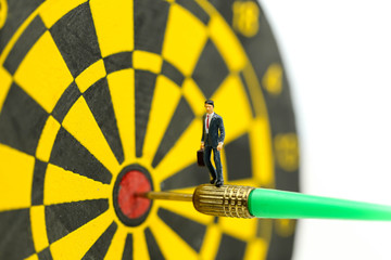 Miniature people: businessman on dart arrow hitting in the target center of dartboard,Target...