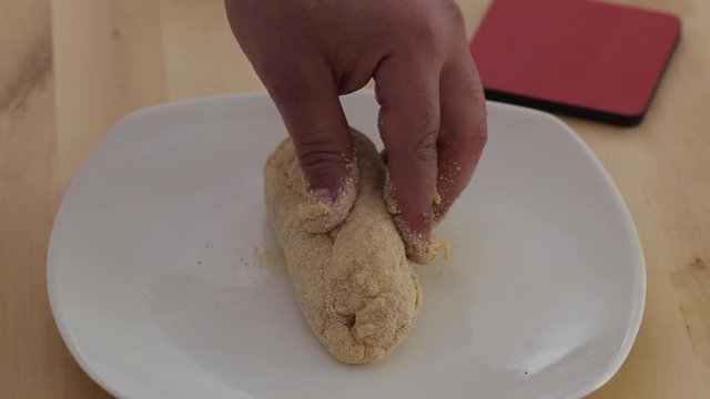 Placing plain dough onto clean, empty white plate on a wooden workboard in a kitchen