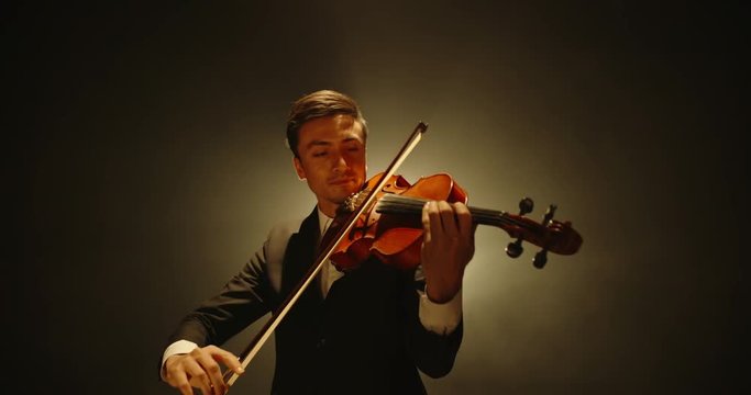Asian violinist performing on stage. Popular musician playing solo on his his instrument on smoked black background 4k footage