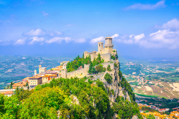 Fototapeta na wymiar Republic San Marino Prima Torre Guaita first fortress tower with brick walls on Mount Titano stone rock with green trees, aerial top panoramic view of landscape valley and hills of suburban district