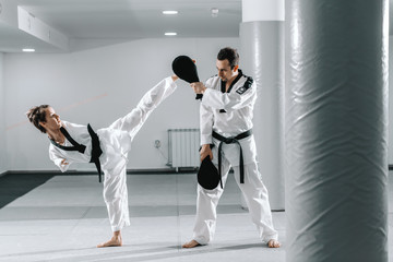 Caucasian handicapped highly motivated girl practicing taekwondo with her training. Girl kicking...