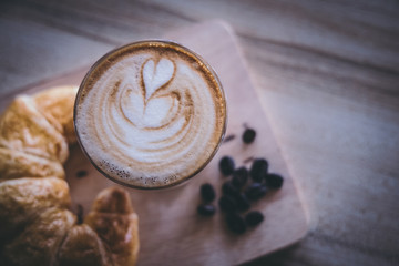 Top view cup of coffee and art latte foam on a black wooden table near the window.