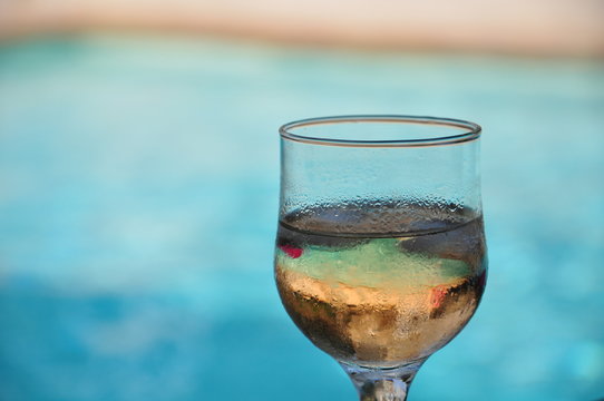 drinking a glass of fresh white wine on pool bar with turquoise blurred background cote azur
