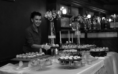 table with sweets and a variety of sweet snacks against the backdrop of  a girl confectioner