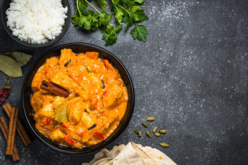 Chicken tikka masala with rice on black top view.