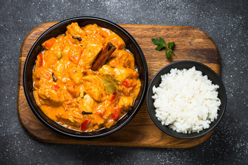 Chicken tikka masala with rice on black top view.