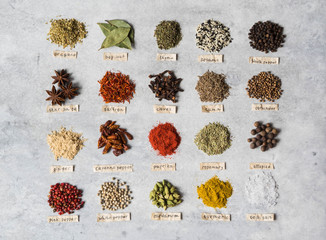 Various dry spices piles and paper lettering flat lay on gray background. Top view