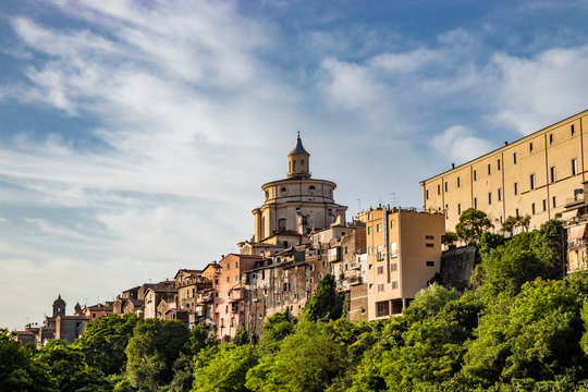 A view of the city of Zagarolo, with the houses built sheer above a tuff hill. Above the roofs the dome of the church of San Pietro appears. The valley full of trees. Province of Rome, Lazio