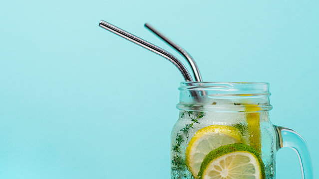 Cold Drink In Mason Jar With Metal Straw On Blue Background. Lemonade Or Detox Water With Lime And Thyme In Glass Jar With Copy Space For Text Or Design. Recyclable Straws, Zero Waste Concept. Banner.