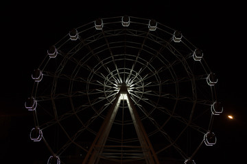 Ferris wheel on dark background, part of Ferris wheel with backlight on black sky background at night