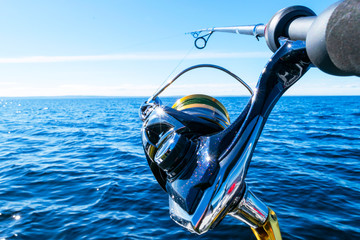 Fishing rod spinning with the line close-up. Fishing rod in rod holder in fishing boat due the...