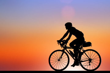 Obraz premium Silhouette man and bike relaxing on blurry sunrise sky background.