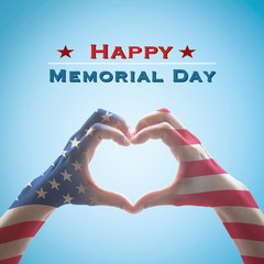 Happy memorial day with America flag pattern on people hands in heart shape isolated on blue sky...