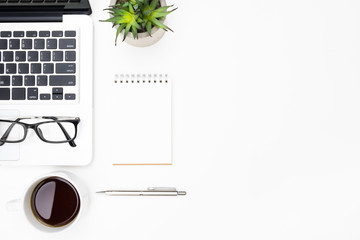 White office desk table with blank notebook, laptop computer, cup of coffee and supplies. Top view with copy space, flat lay.