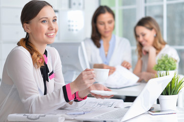 Portrait of young women sit at the table and work in a modern office