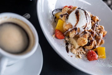 waffles with chocolate covered ice cream and decorated with fruit on a plate on the table